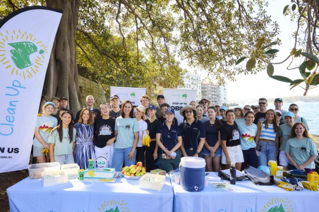 Image of Clean Up Australia volunteers standing in a park behind trestle tables 