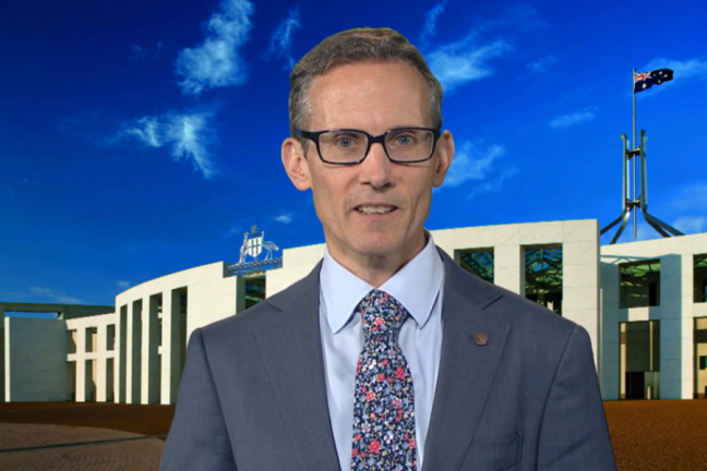 Image of man in a suit in front of Parliament House