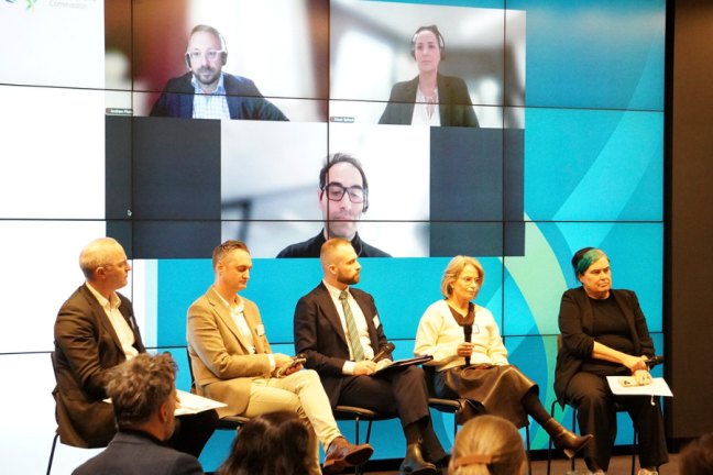 Five people sitting on a stage at a conference. 